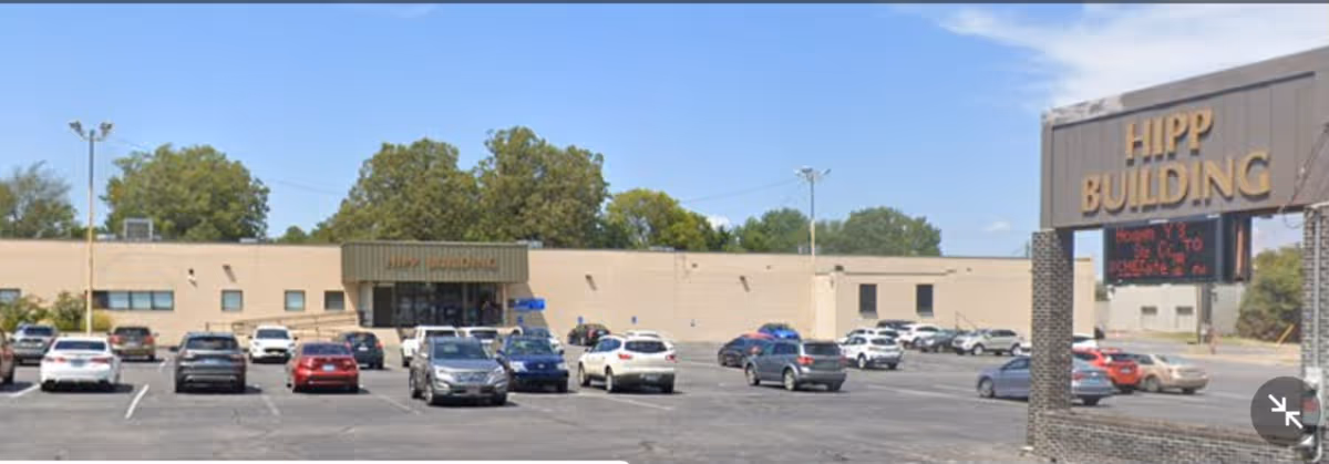 Parking lot in front of a beige building with cars and a large Hipp Building sign.