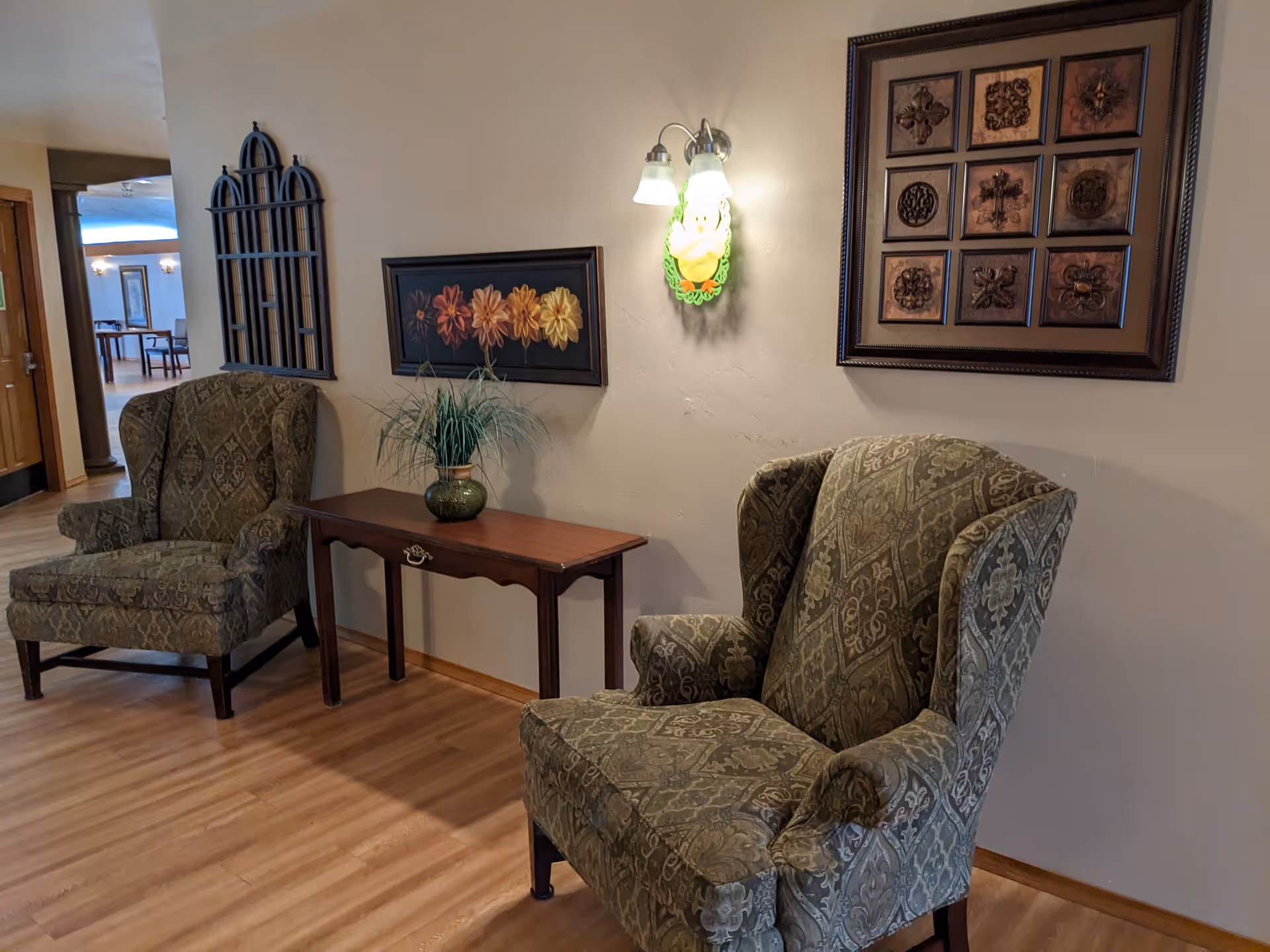Two patterned armchairs flank a wooden console table with wall art in a cozy living room.