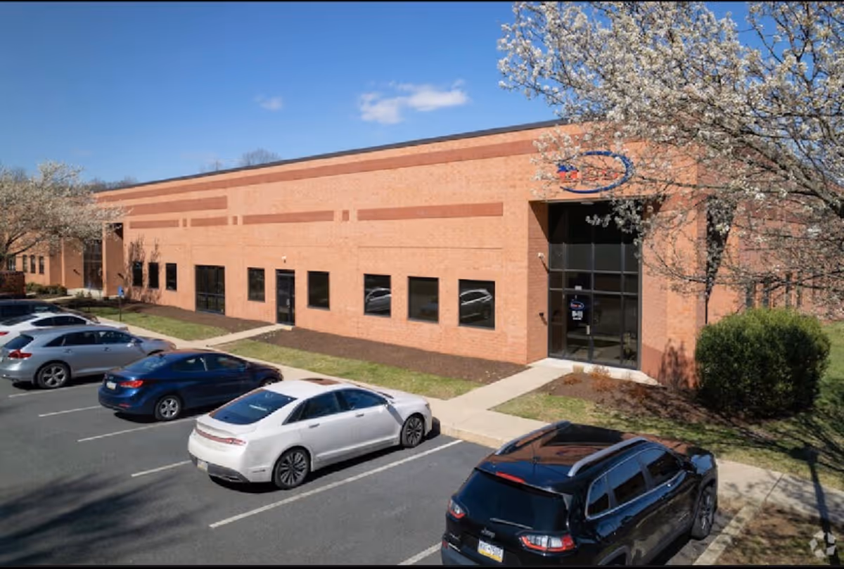 Brick healthcare facility exterior with glass entrance and a parking lot.