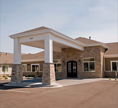 Sunridge Assisted Living front entrance with stone columns and covered porte-cochere.