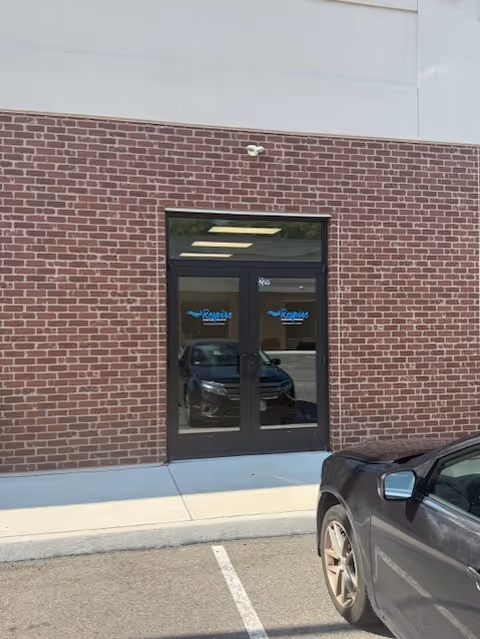 Brick building exterior with glass doors showing Respire signage and a parked car.