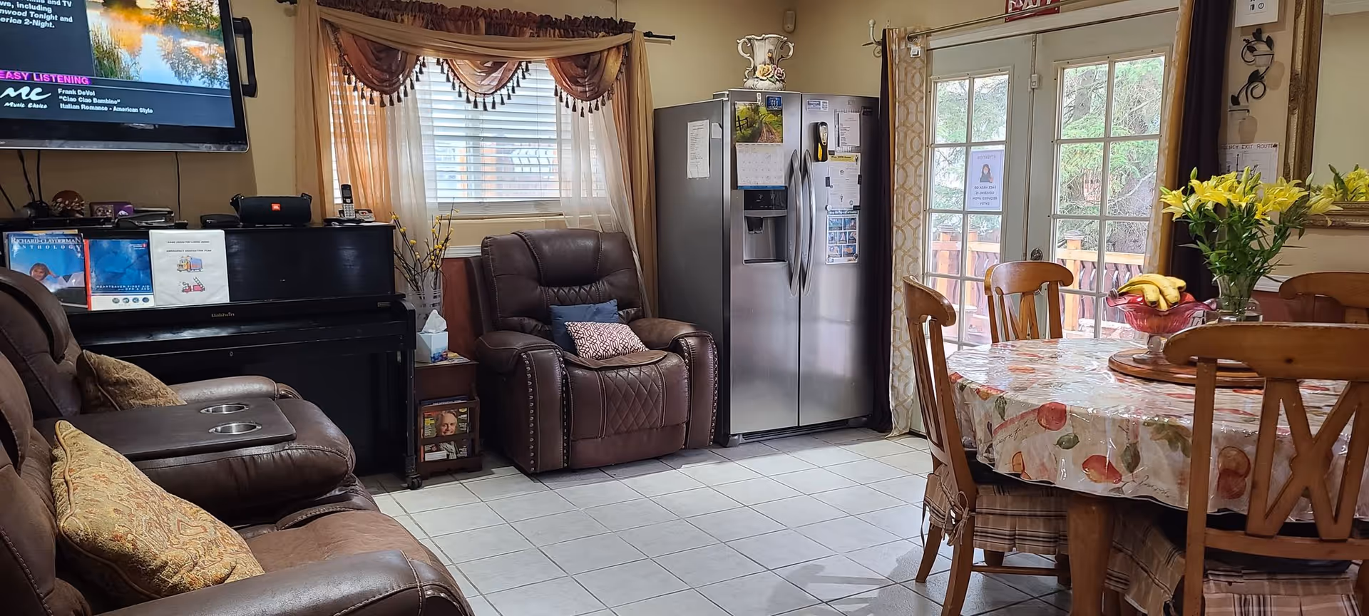 Cozy living area featuring brown leather recliners, a dining table, and a stainless steel refrigerator.