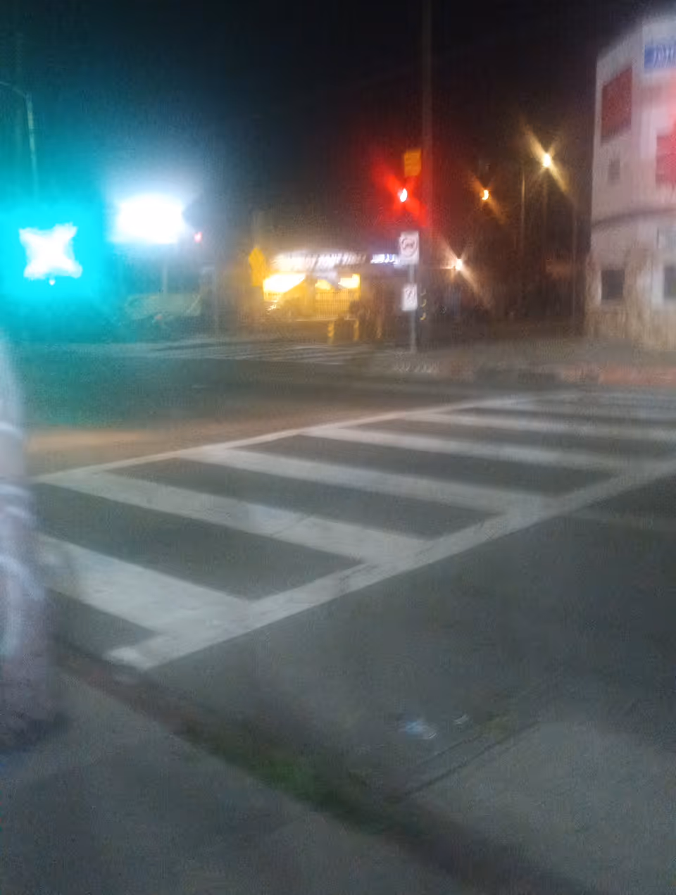 Nighttime street scene with a crosswalk, traffic lights, and a building on the right.