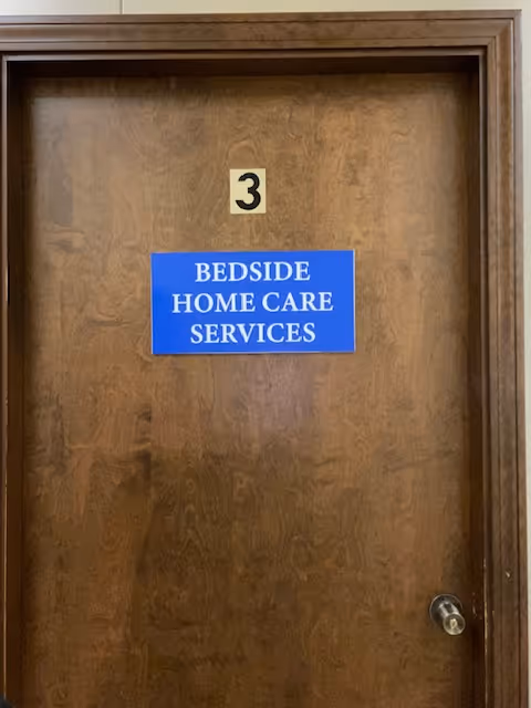 Wooden door with blue sign reading Bedside Home Care Services and number 3.