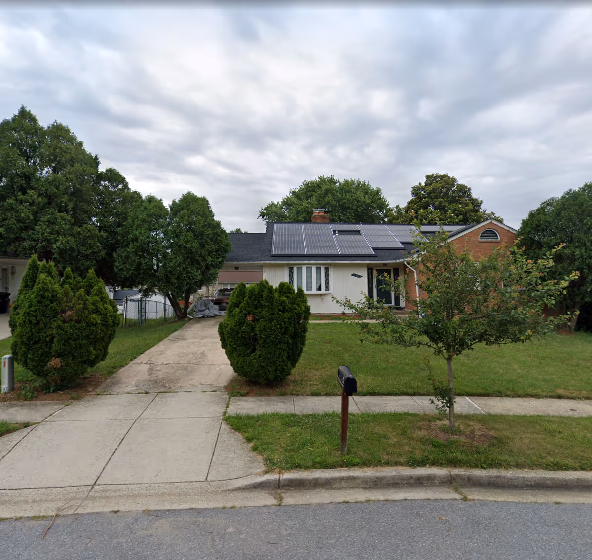 A single-story house with solar panels and a front lawn on a quiet street.