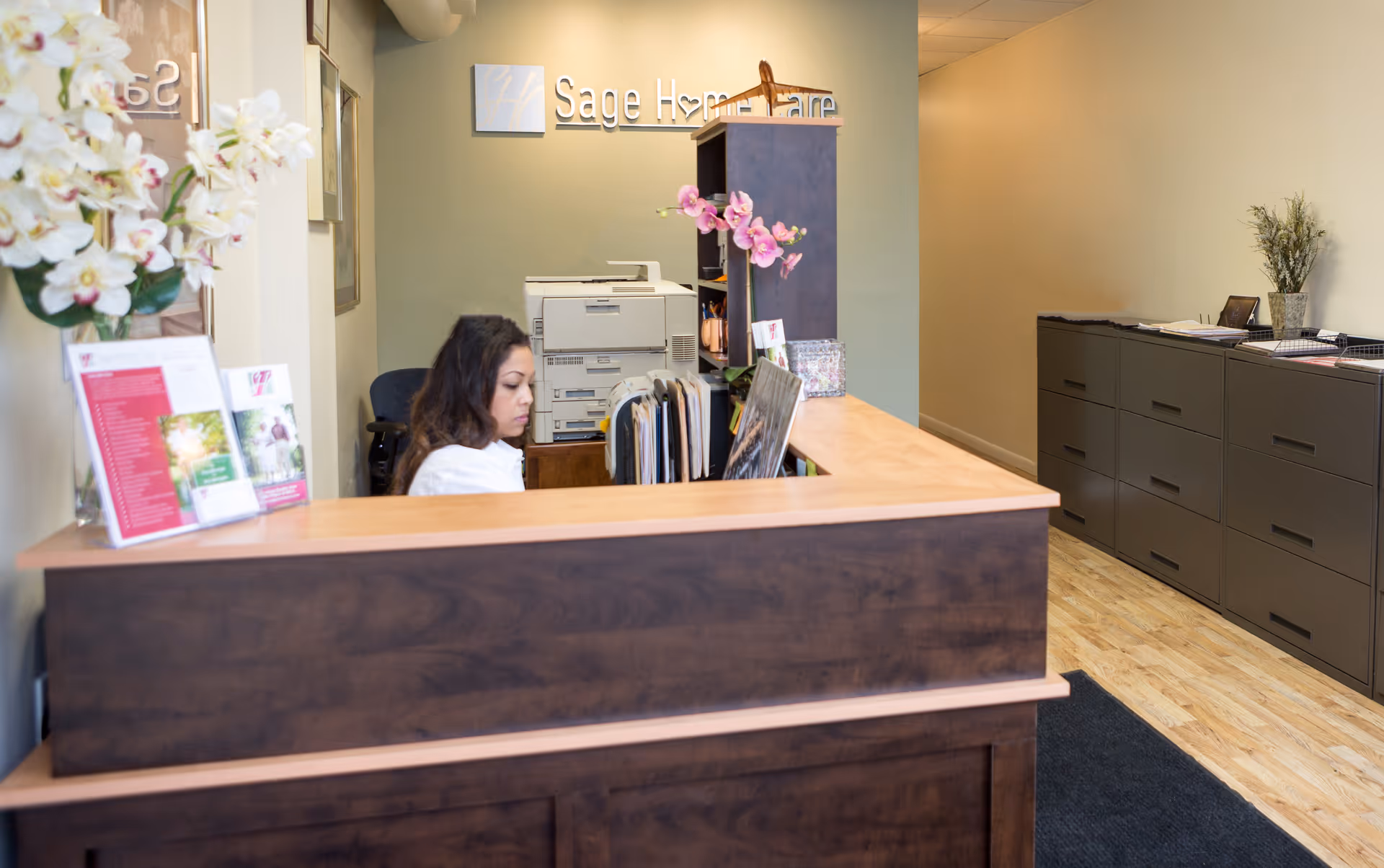 Reception desk in a Sage Home Care lobby with a receptionist at work.