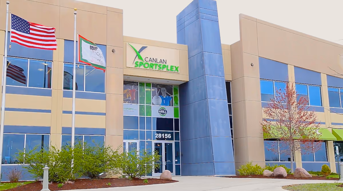 Front view of Canlan Sportsplex exterior with flags, glass windows, and the entrance.