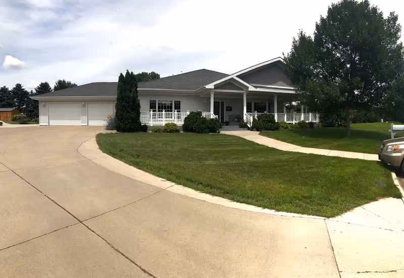 Prairie Home Hospice Lockwood House front exterior with porch and lush lawn.
