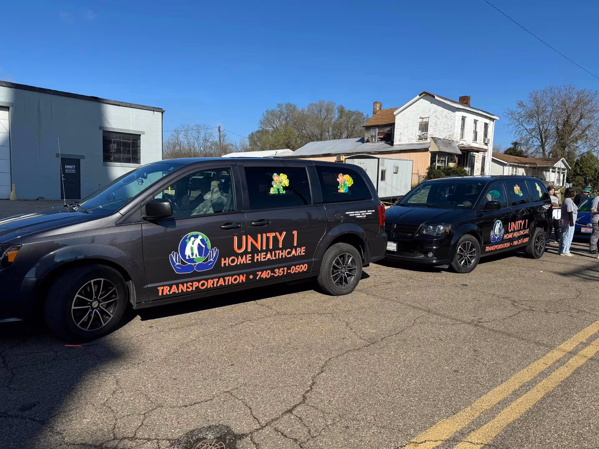 Unity 1 Home Healthcare transportation vans parked along a street with buildings behind.