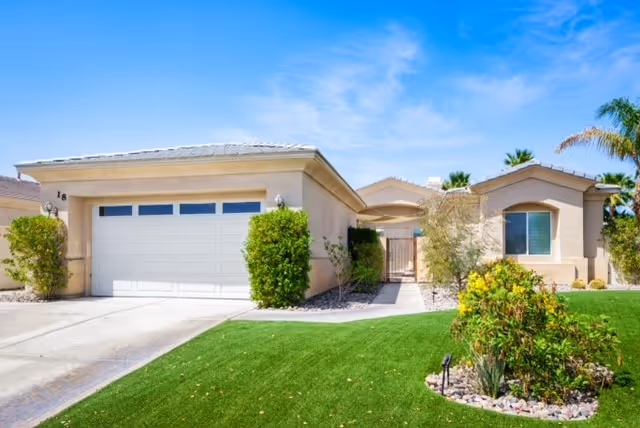 Residential-style facility exterior with a two-car garage and manicured front lawn