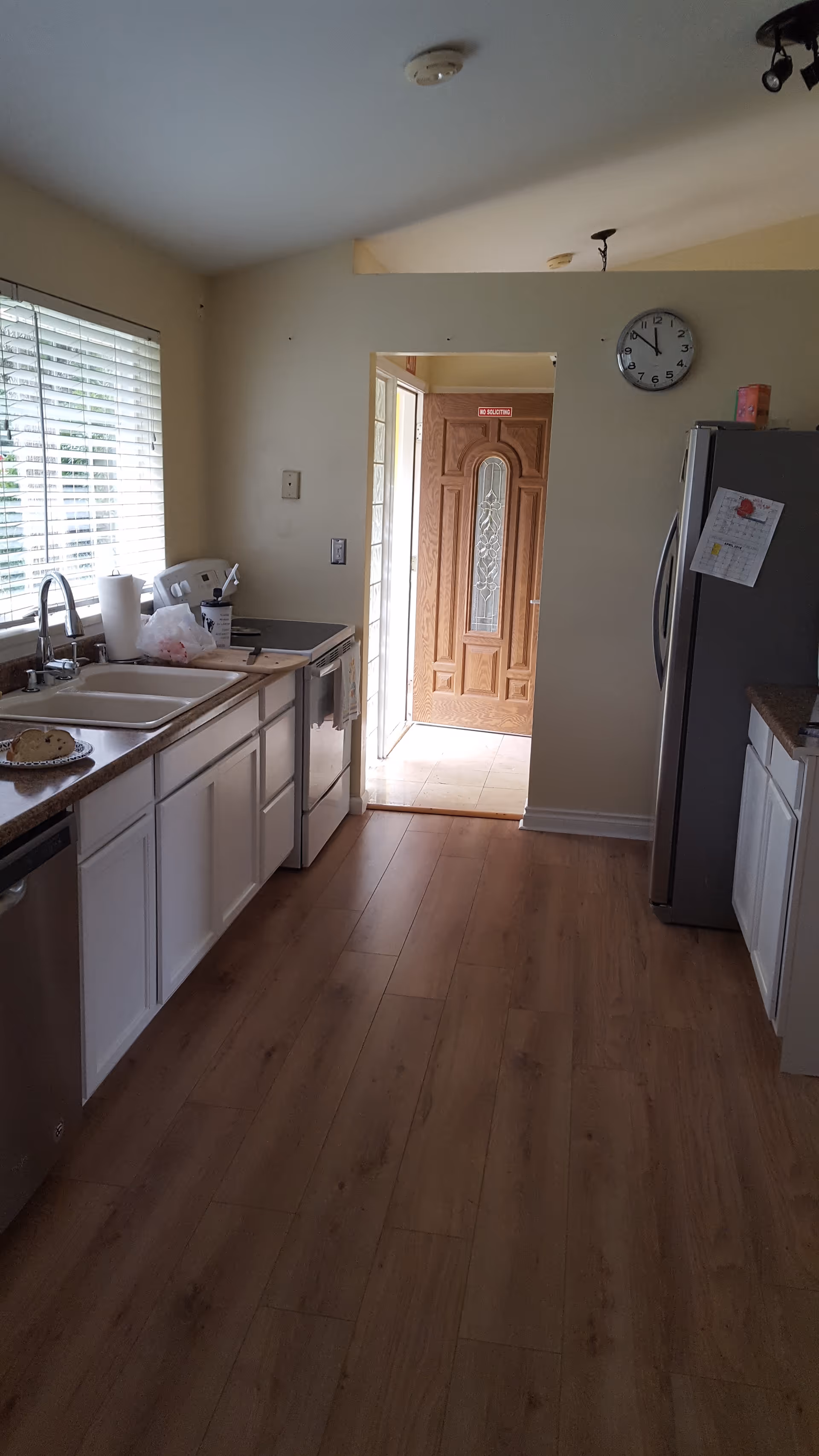 A small kitchen with white cabinets, stainless appliances, and a door to the outside.