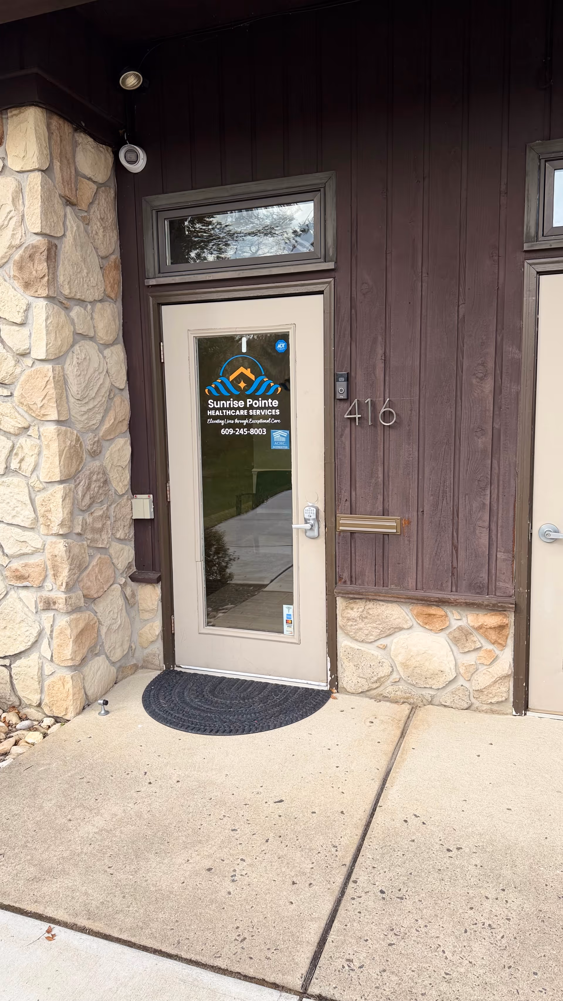 Front entrance of Sunrise Pointe facility with stone walls, wood siding, and a door.