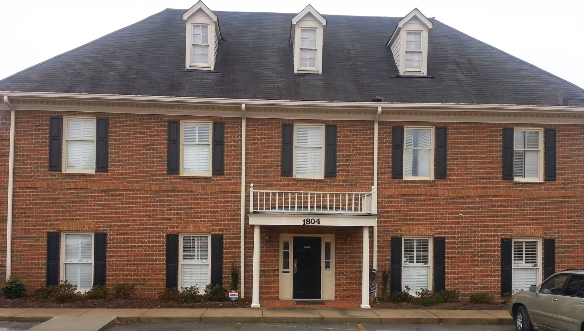 Brick, multi-story senior living facility exterior with a central covered entry and shuttered windows.