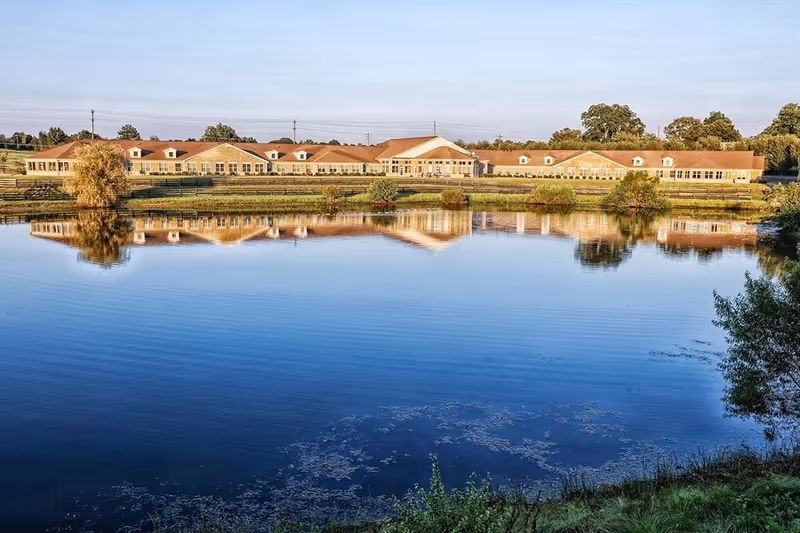 Country Square senior living facility sits along a lake with the building reflected in water