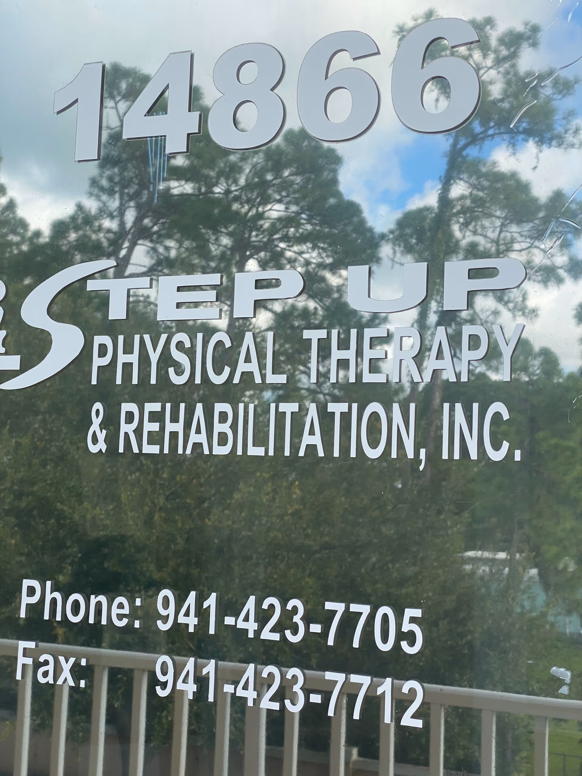 Glass storefront sign for Step Up Physical Therapy and Rehabilitation, Inc. with phone numbers.