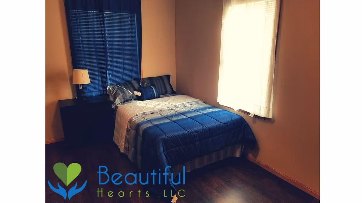 A small bedroom in a senior living facility with blue bedding and a nightstand.