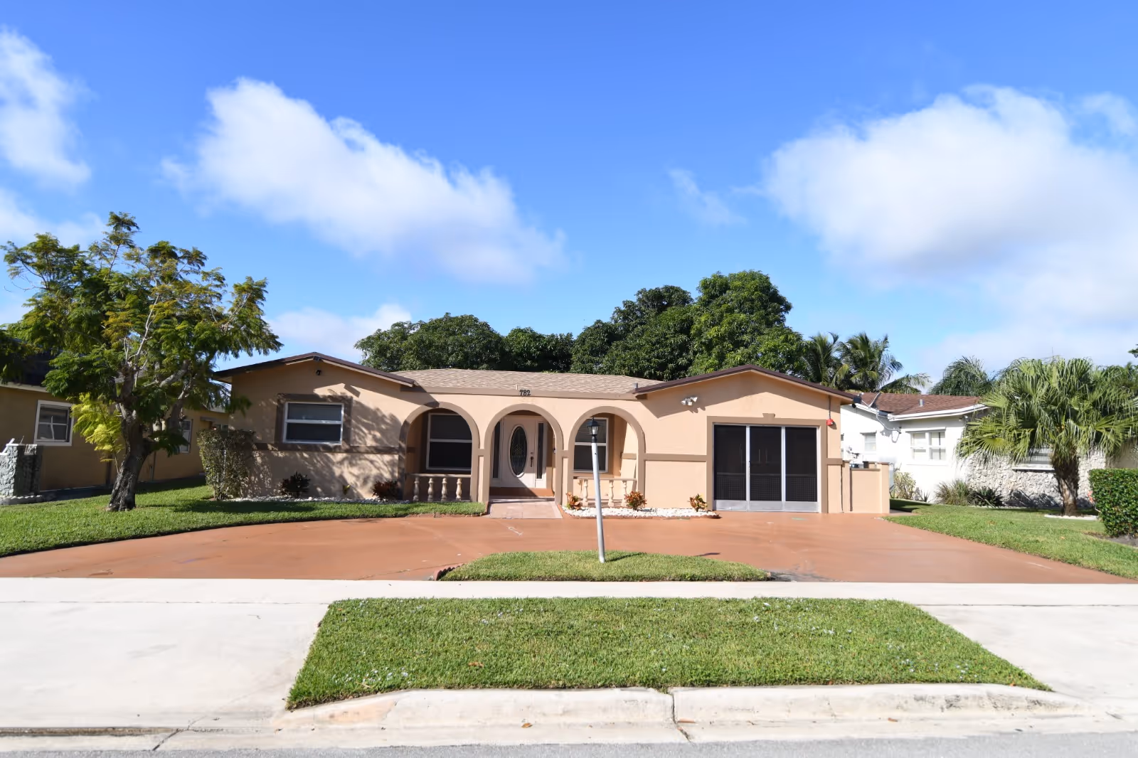Peach-colored, single-story building with arches and a wide front driveway.
