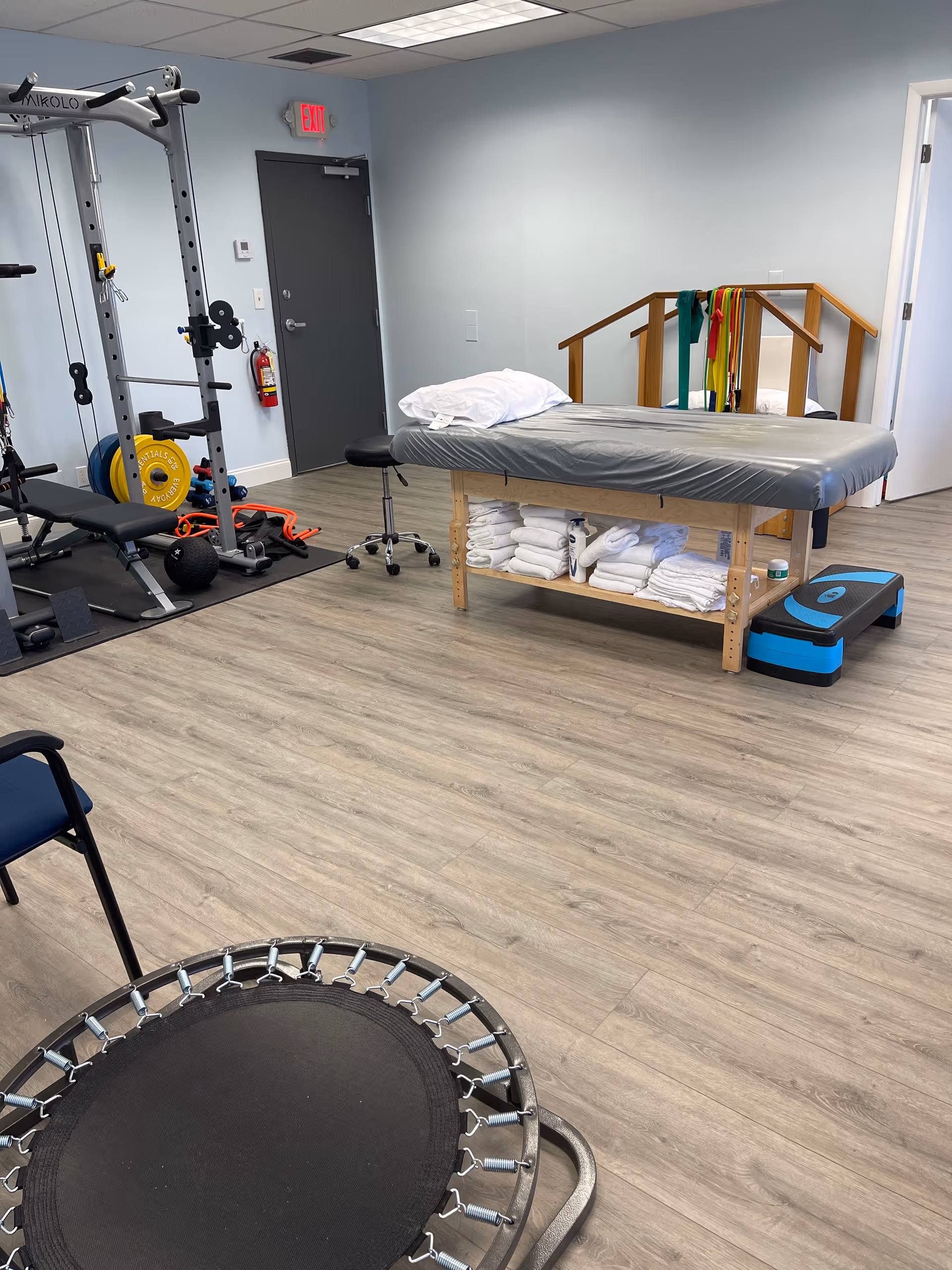 Interior physical therapy room with a treatment table, weights, and exercise equipment.