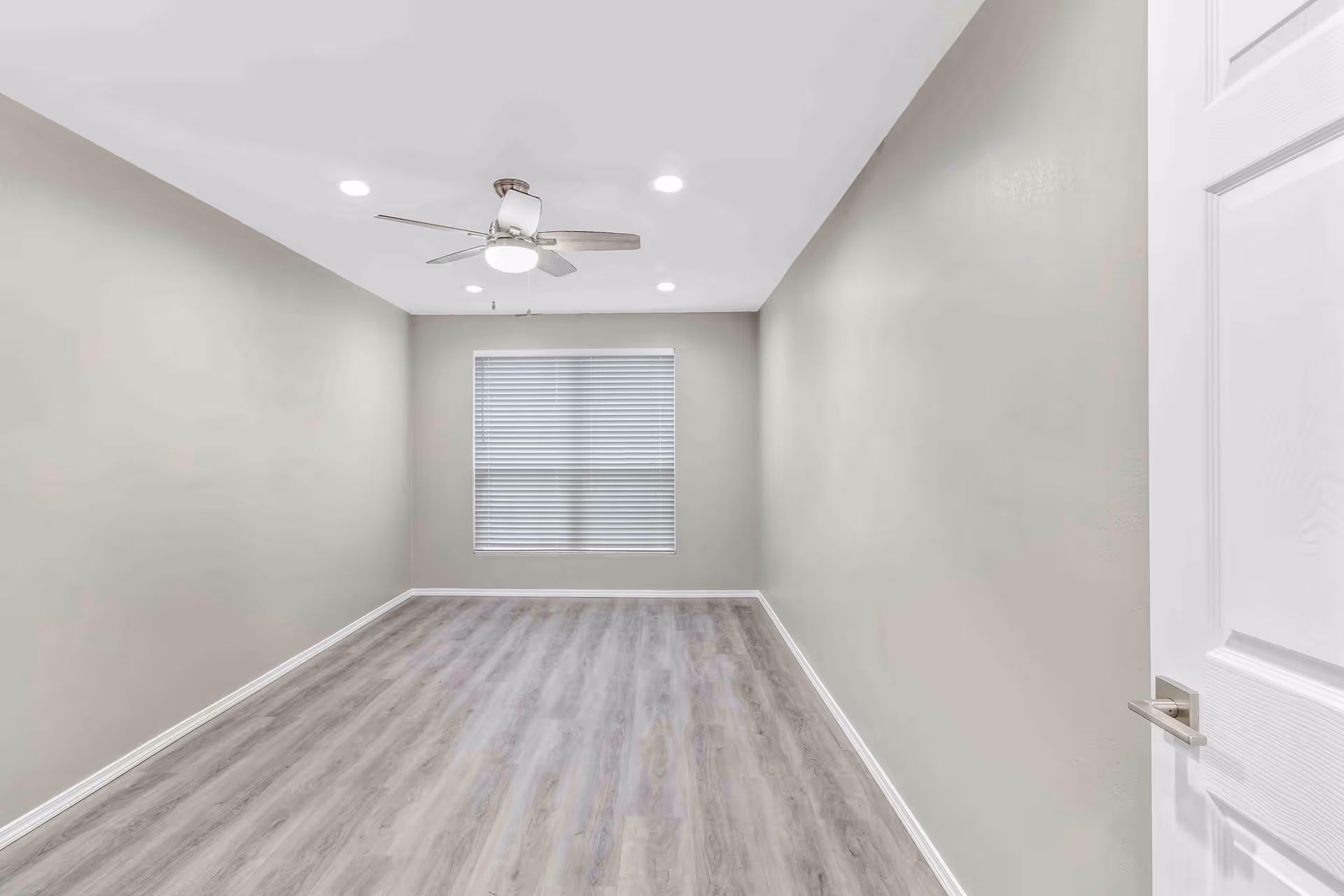 Empty room with wood-look flooring, a ceiling fan, recessed lights, and a window with blinds.