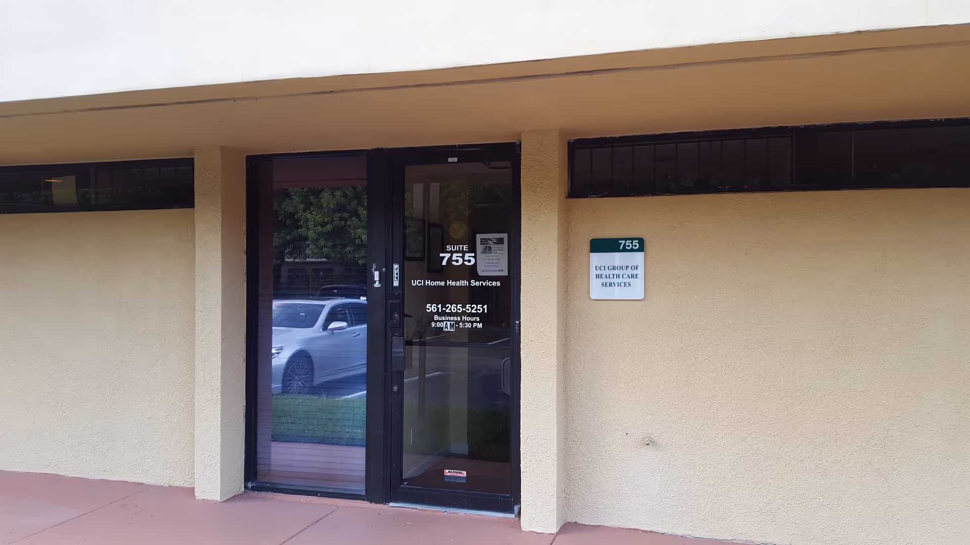 Exterior view of beige building entrance with a glass door and UCI Home Health Services signage.