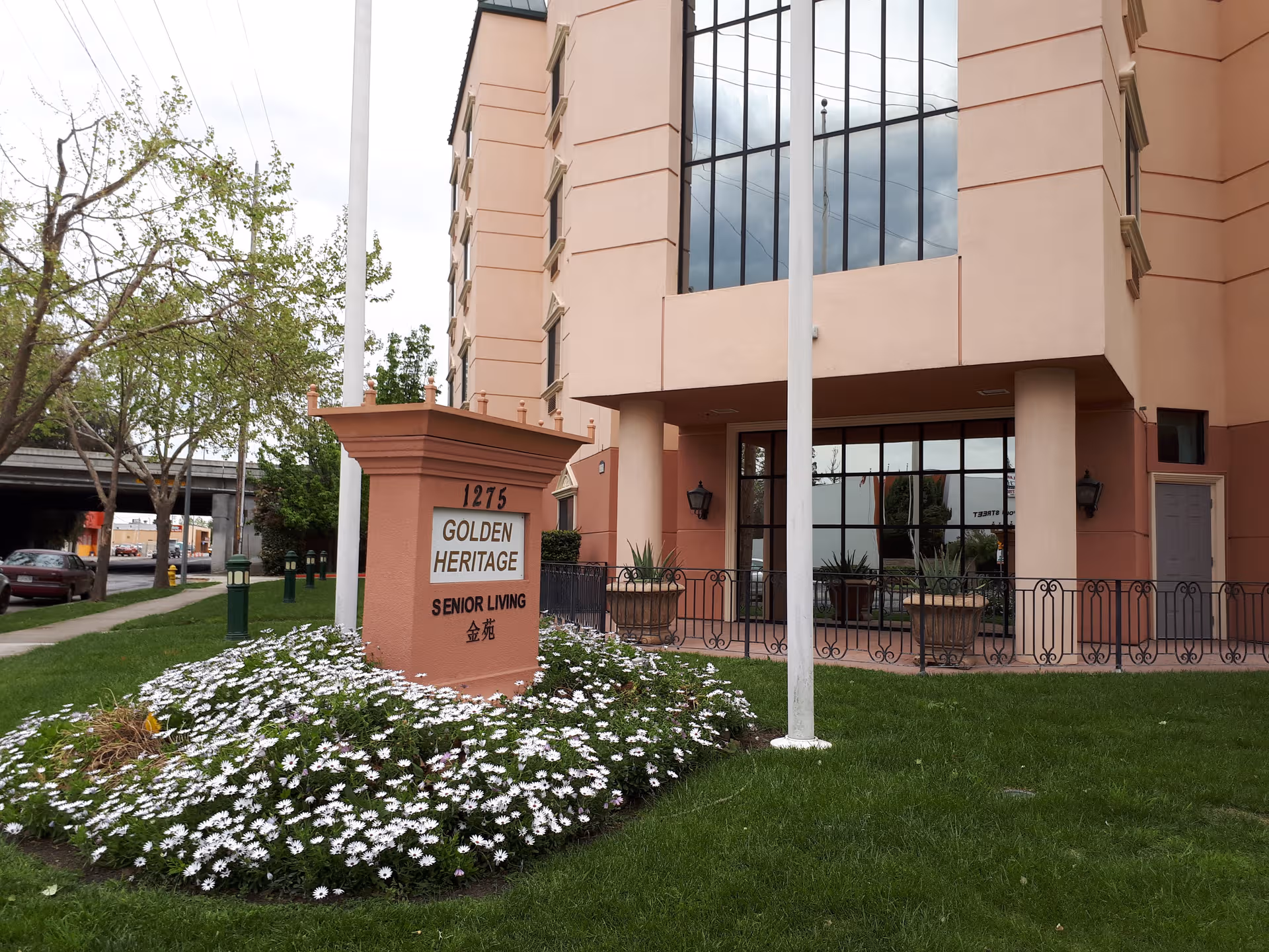 Exterior view of Golden Heritage Living building with sign and flower bed.
