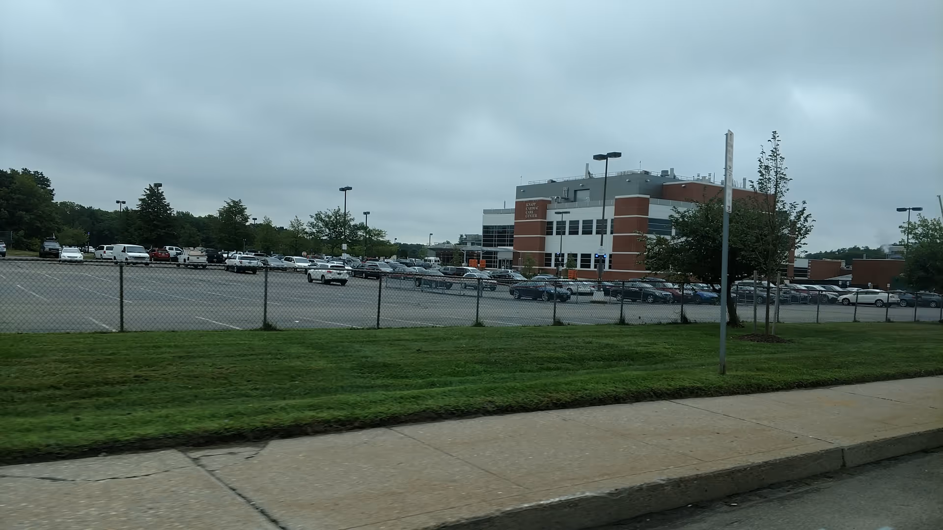 Exterior view of Knapp Cardiac Care Center with a fenced parking lot and cars