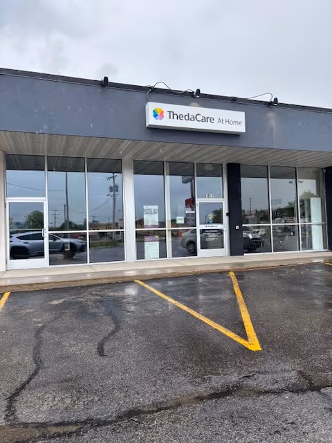 Exterior view of ThedaCare At Home Oshkosh storefront with glass doors and parking lot.