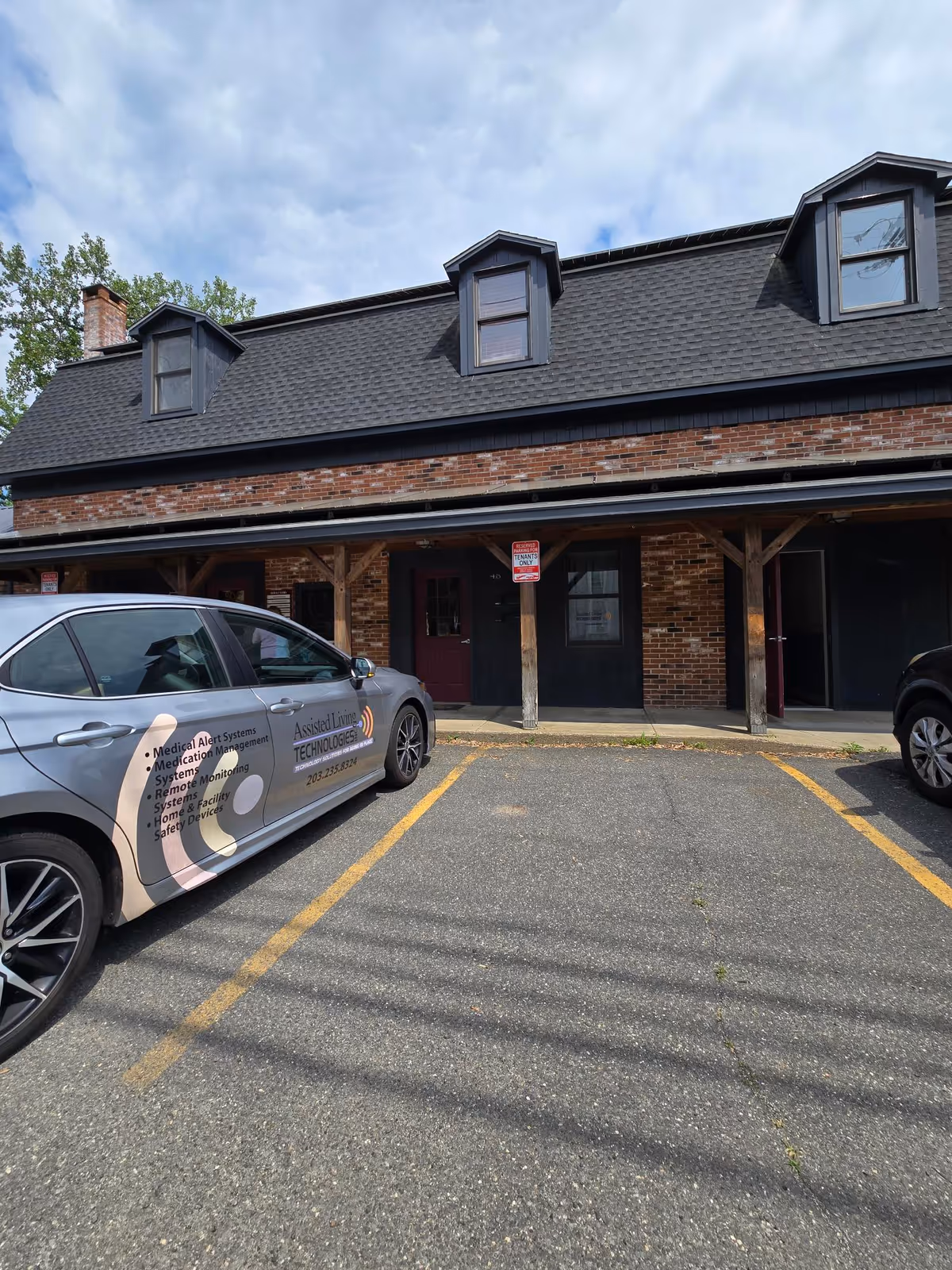 Exterior view of an assisted living facility with a branded car in a parking lot.