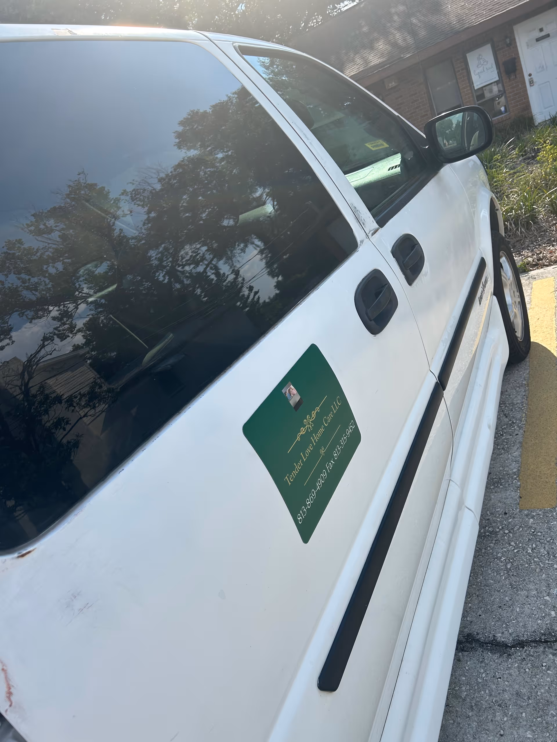 White van with Tender Love Home Care LLC sticker parked near a building.