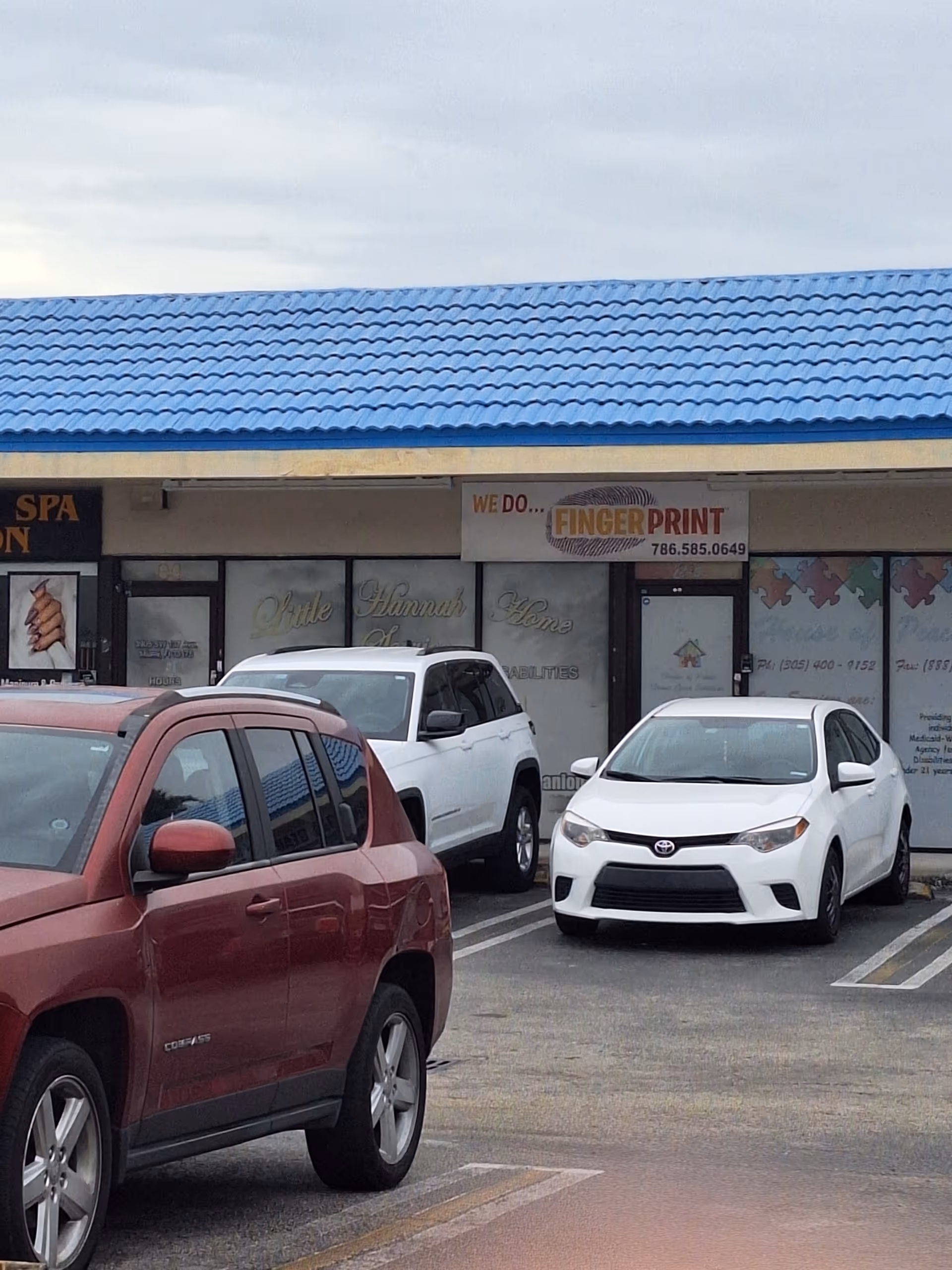 Exterior of a strip plaza featuring Little Hannah Home Services storefront and parked cars.