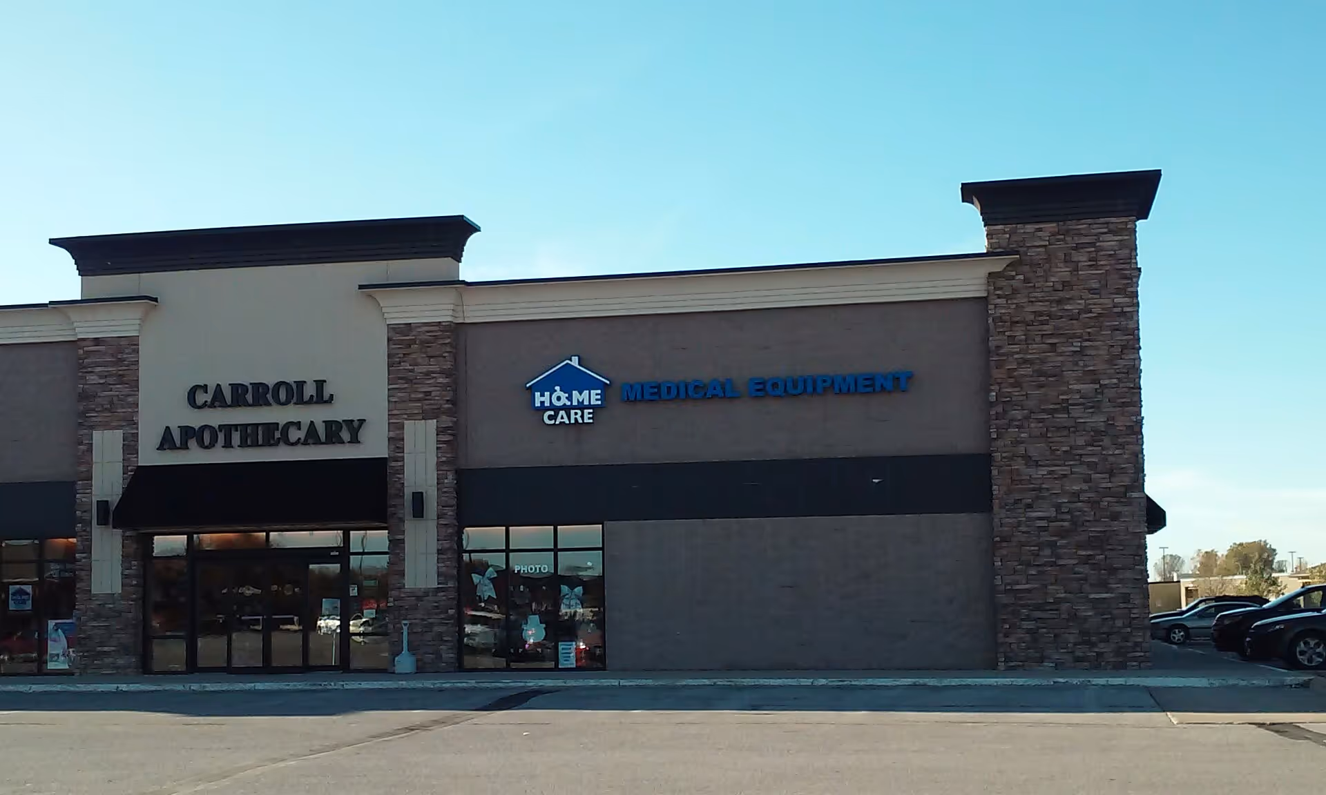 Exterior storefronts of a strip mall, with signs for Carroll Apothecary and Home Care Medical Equipment.