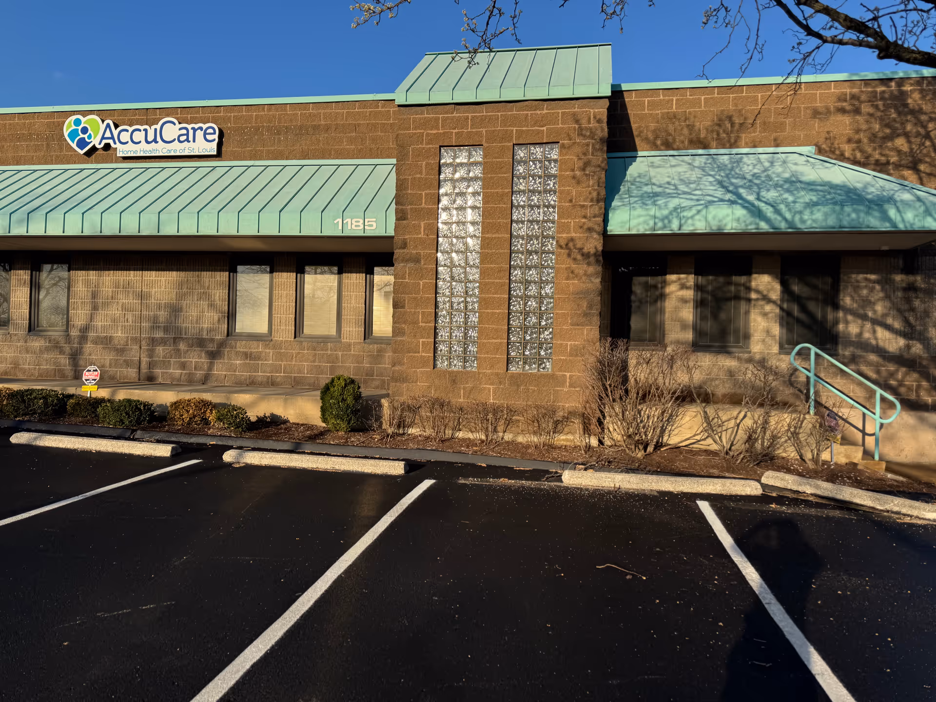 AccuCare building exterior with teal awnings, storefront windows, and a parking lot.
