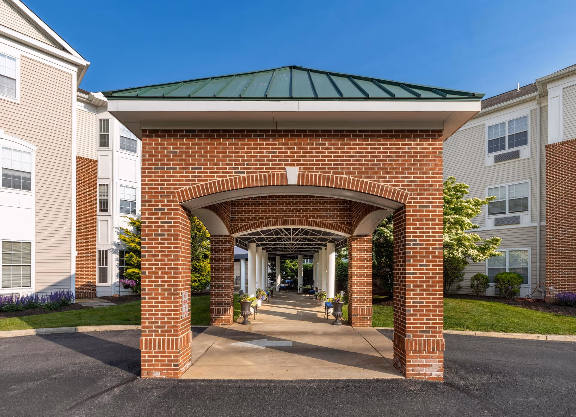 Brick entrance with covered arched walkway to a senior living building.