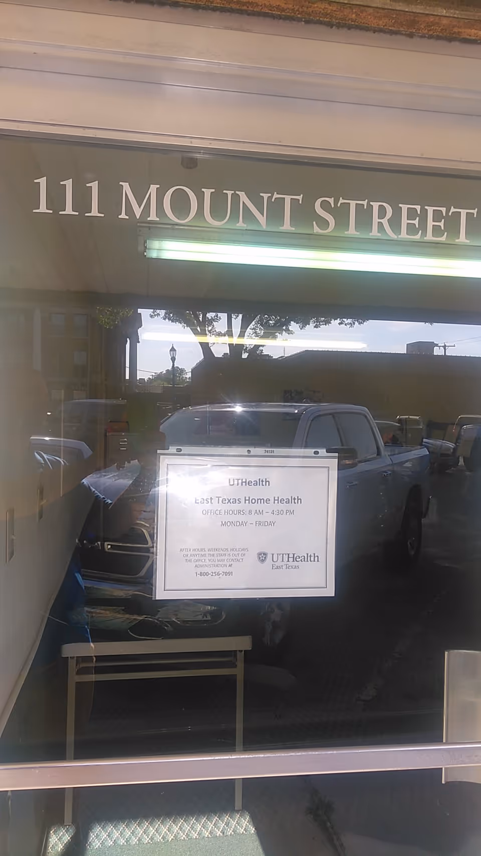 Storefront window shows street address 111 Mount Street and a UT Health sign with parked cars.