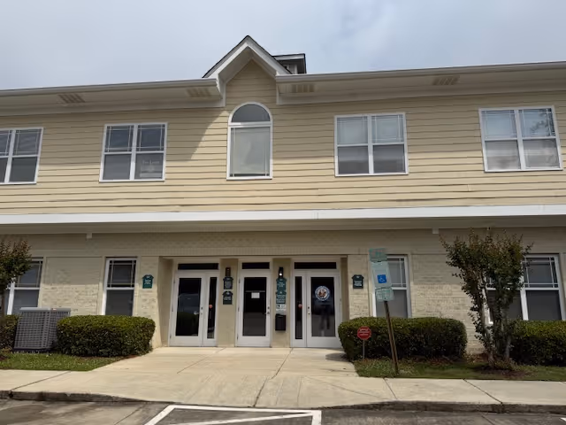 Exterior front of a two-story senior living facility with entrance doors.