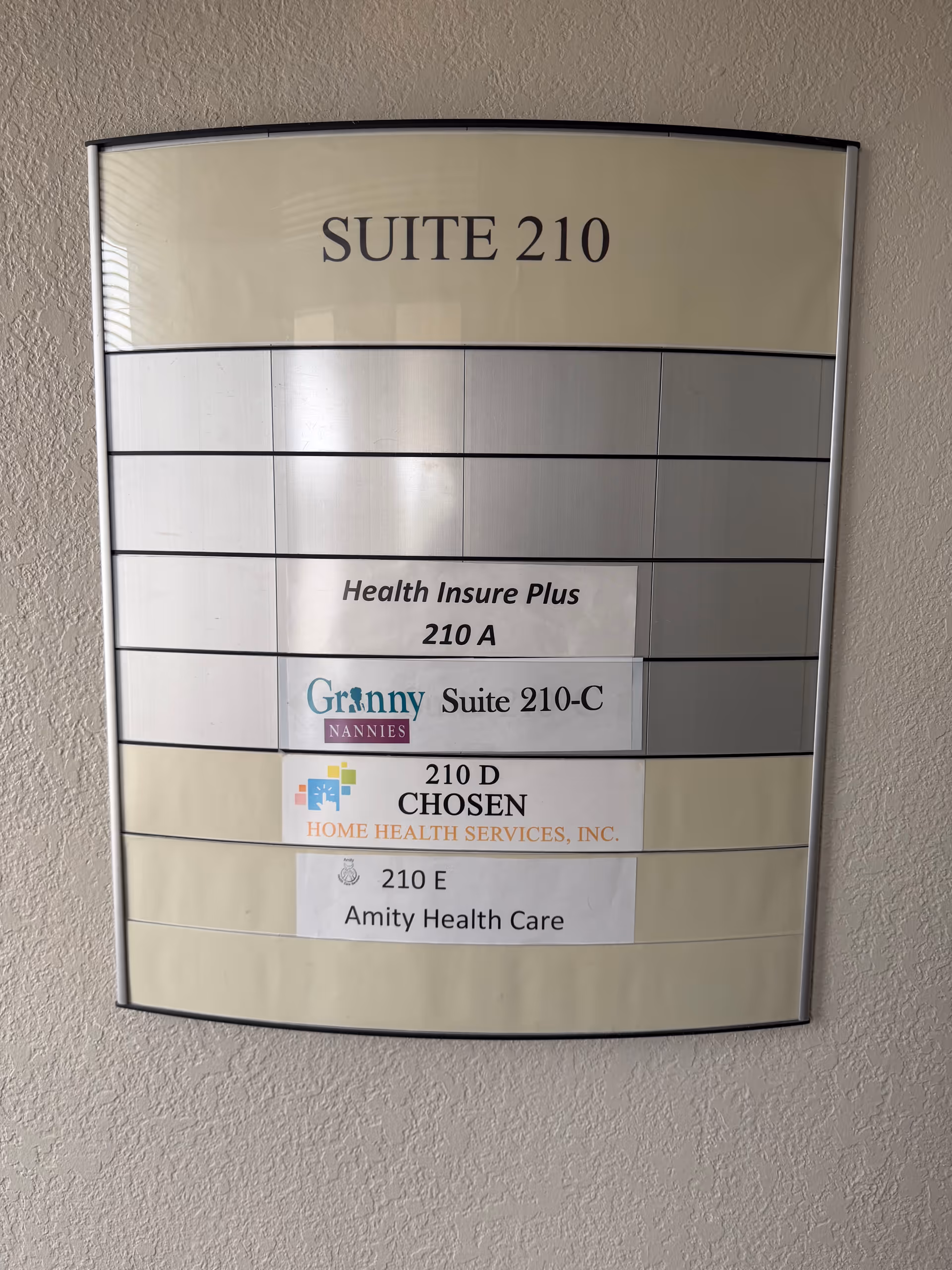Wall-mounted directory sign showing Suite 210 with multiple tenant labels.