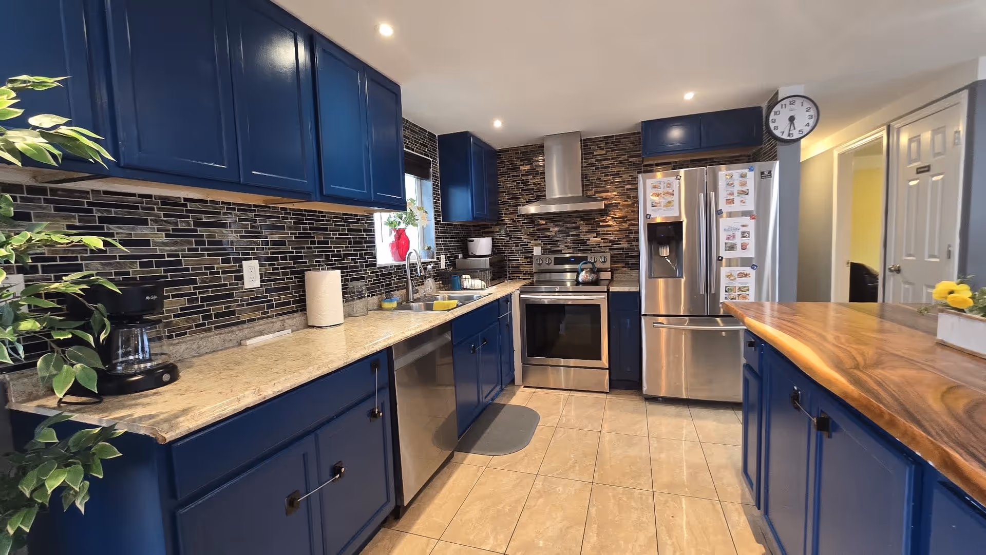 Blue kitchen with stainless steel appliances, granite countertops, and a wooden island.