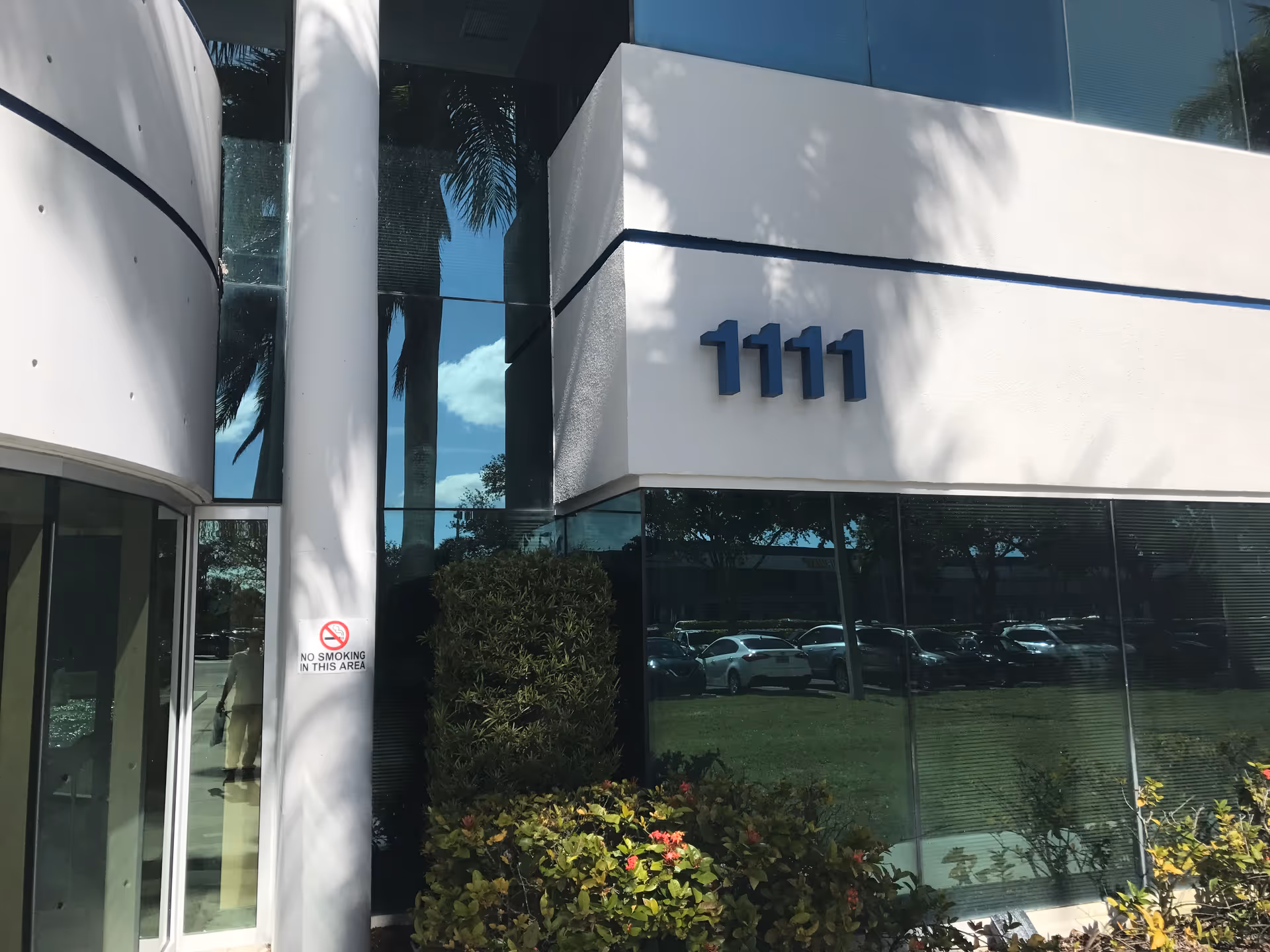 Modern building exterior with glass windows, white facade, and blue number 1111.