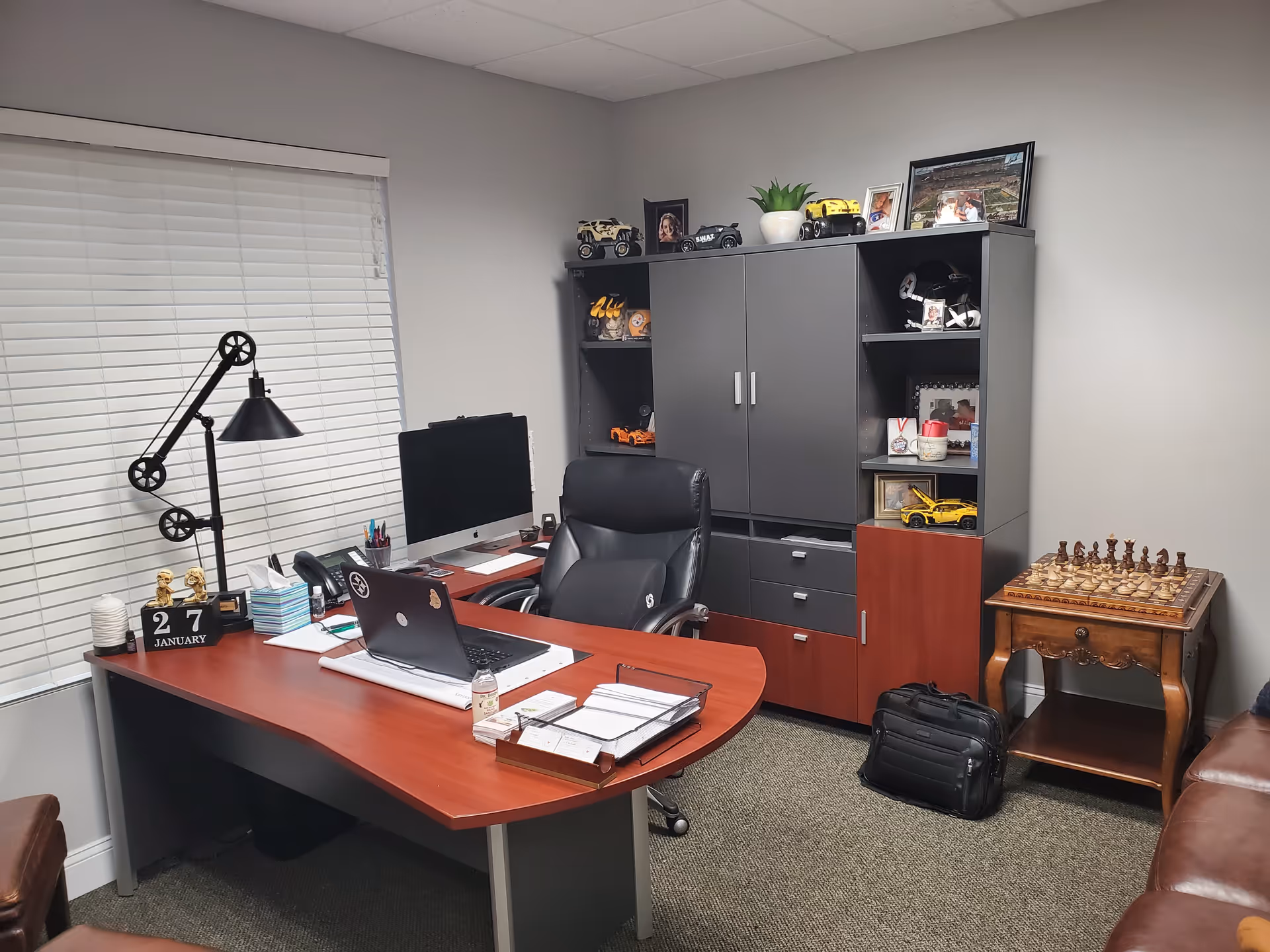 Office workspace featuring a desk, computer station, shelving cabinets, and a chessboard on a side table.