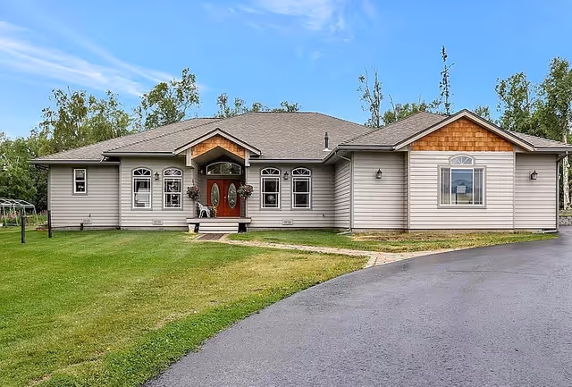A single-story assisted living front building with a curved driveway and green lawn.