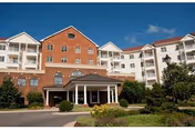 Two-story brick senior living building with a covered entrance and manicured landscaping.