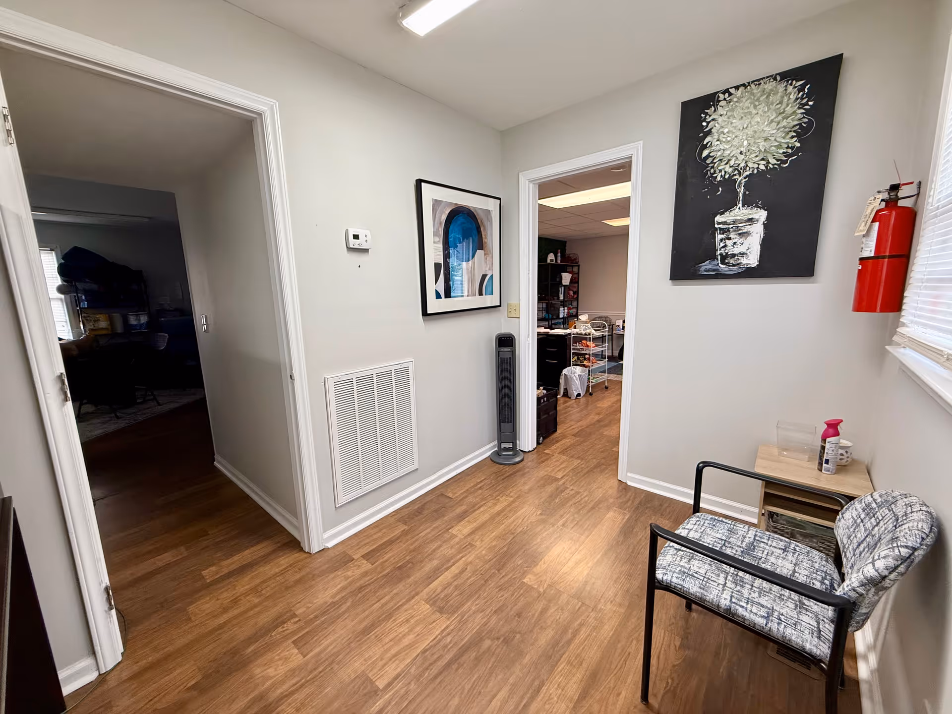Interior hallway of a senior living facility with chair, artwork, and a fire extinguisher.