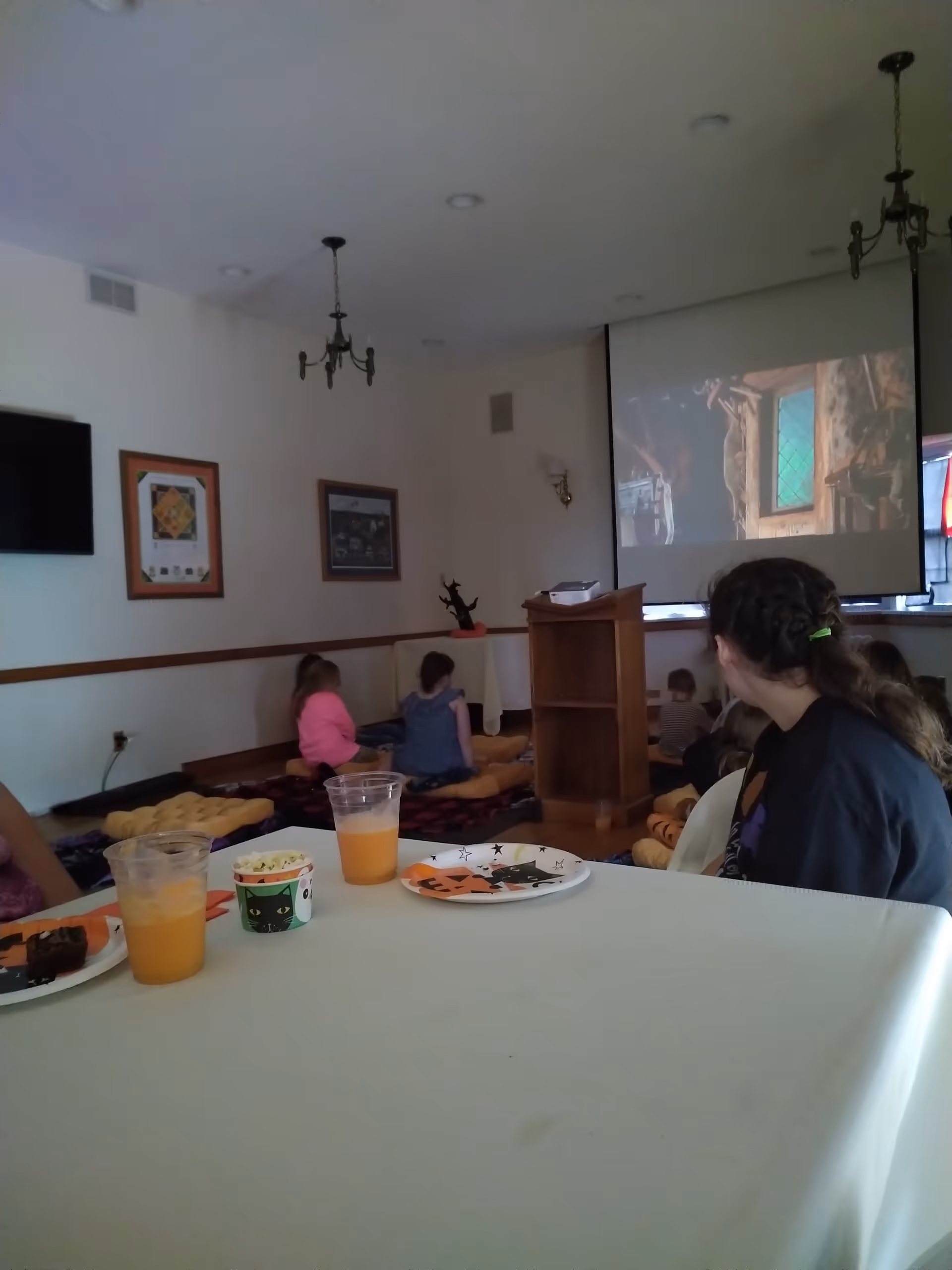 Residents sit on cushions while a projector displays a movie in a common activity room.