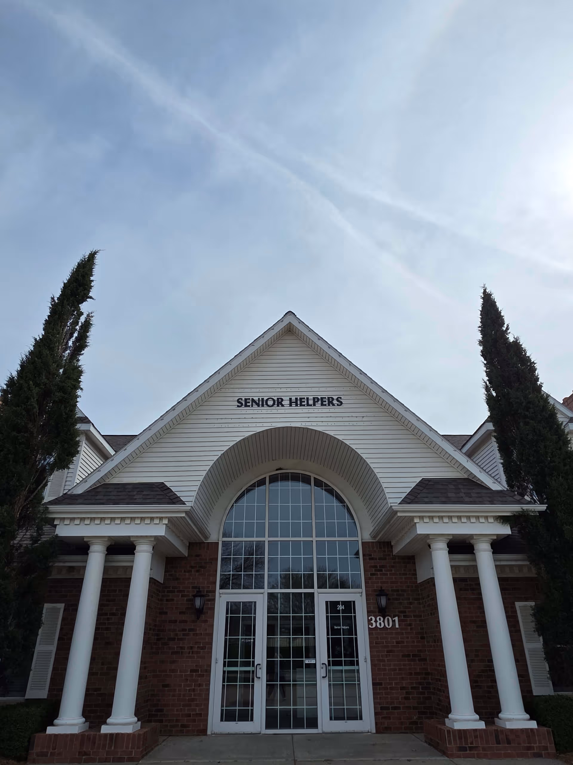 Front view of a Senior Helpers facility with arched entrance and columns.