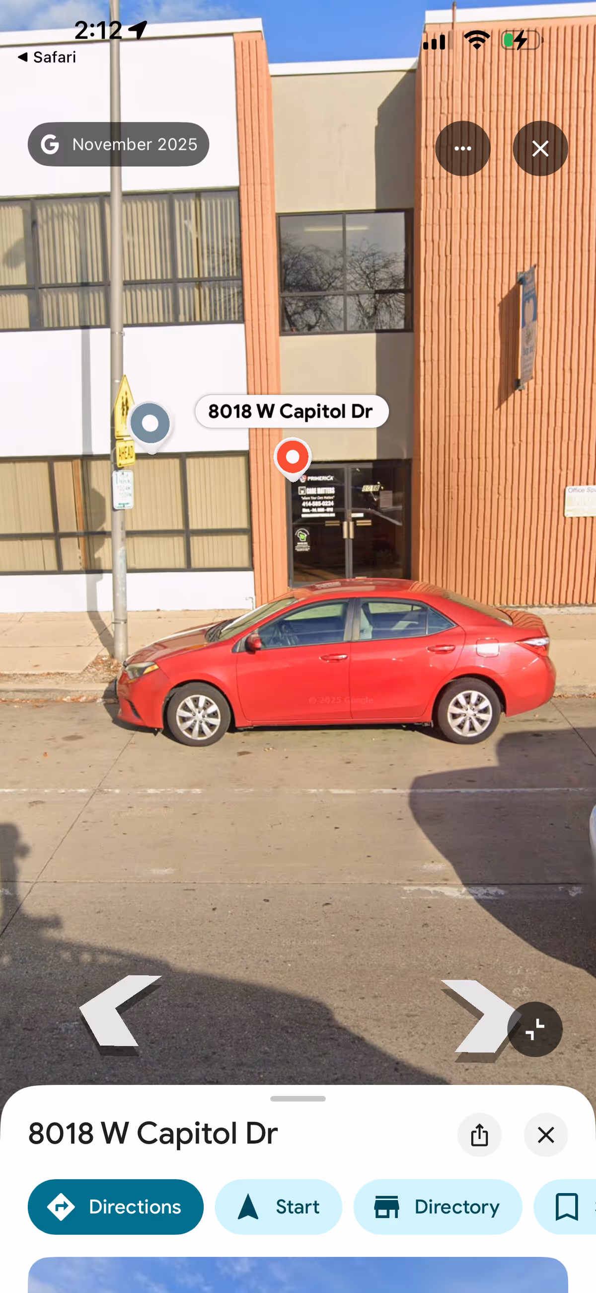 Building exterior of a facility with a red car parked in front.