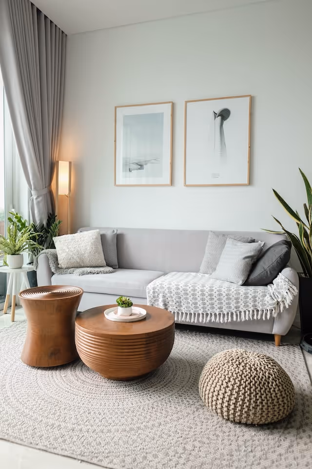 Light gray living room with sofa, plants, and modern wooden coffee tables.