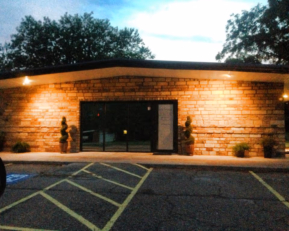 Exterior stone-front building with glass doors and potted plants at the entrance.
