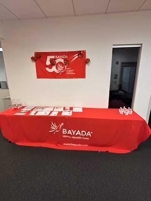 Red Bayada tablecloth and promotional materials on a table in an interior hallway.