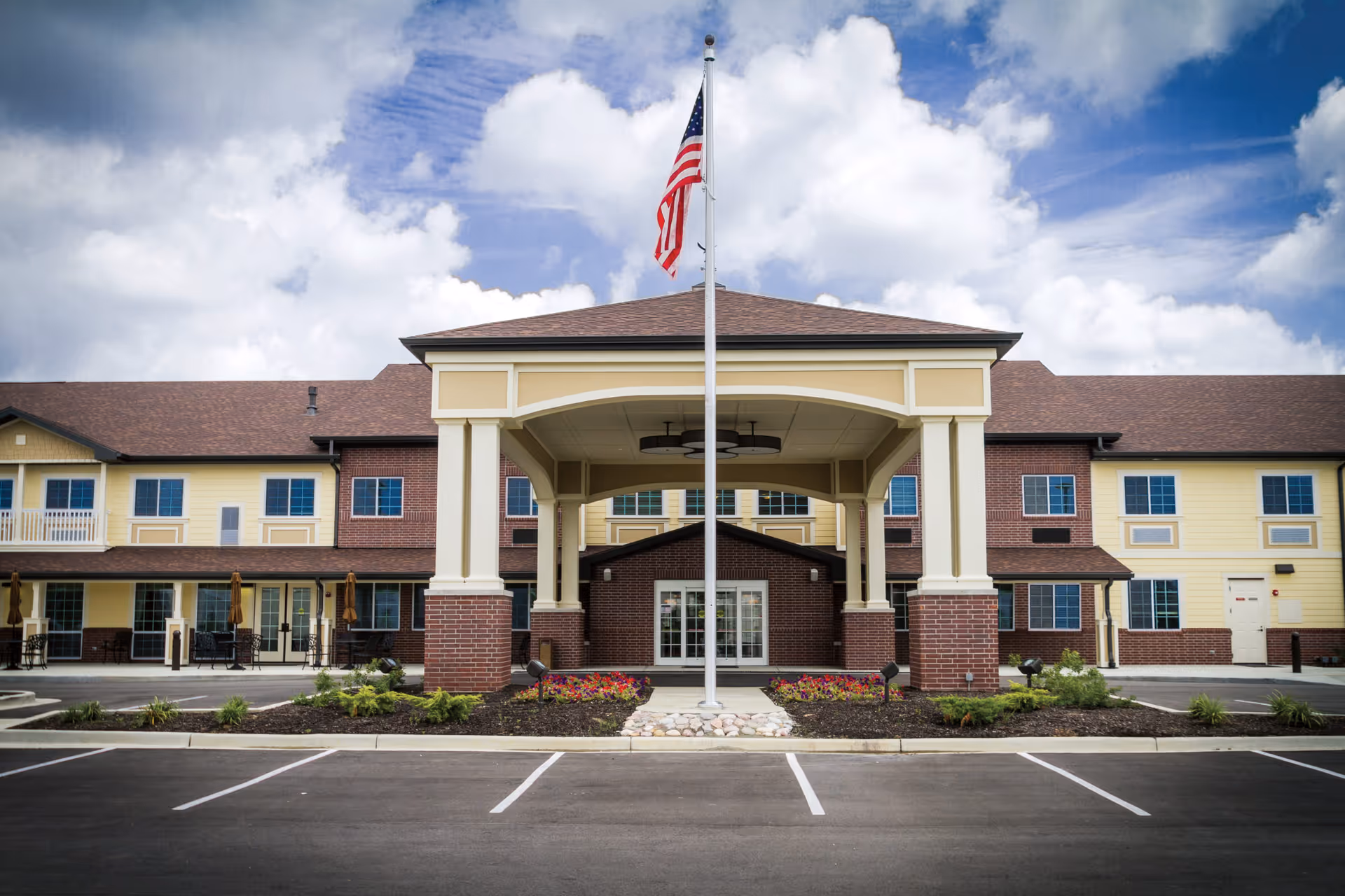 Exterior view of Meadow Brook Senior Living's front entrance with flagpole and brick columns.