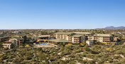 Aerial view of a senior living complex of connected buildings set in a desert landscape under a clear blue sky.